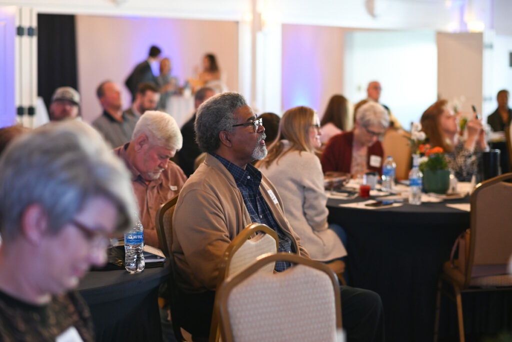 A group of attendees listen to a speaker.