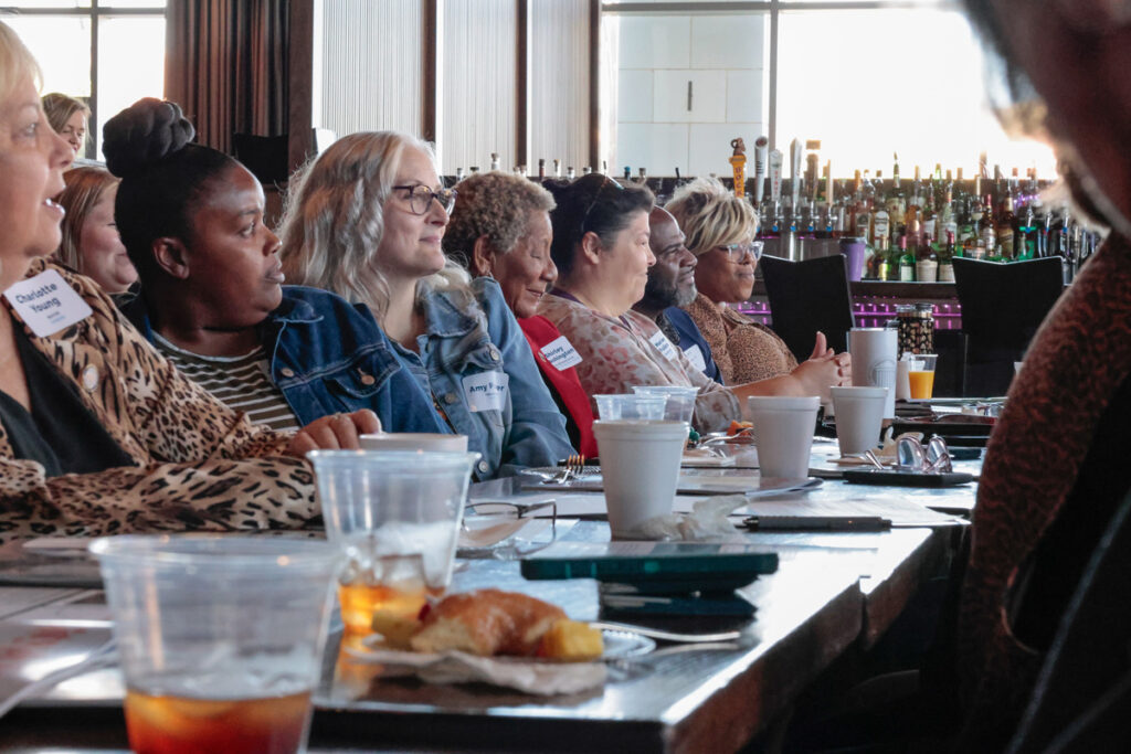 A group of regional meeting participants listen to a speaker.